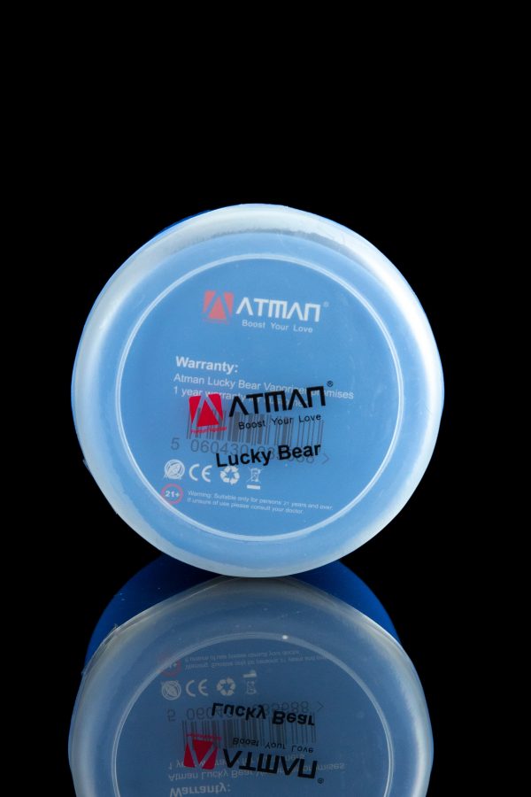 Close-up of a blue “Lucky Bear” cannabis vape cartridge cap with branding and age restriction warning, reflected on a glossy surface.