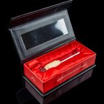 Luxury cannabis pipe presentation box with gold-toned pipe inside.