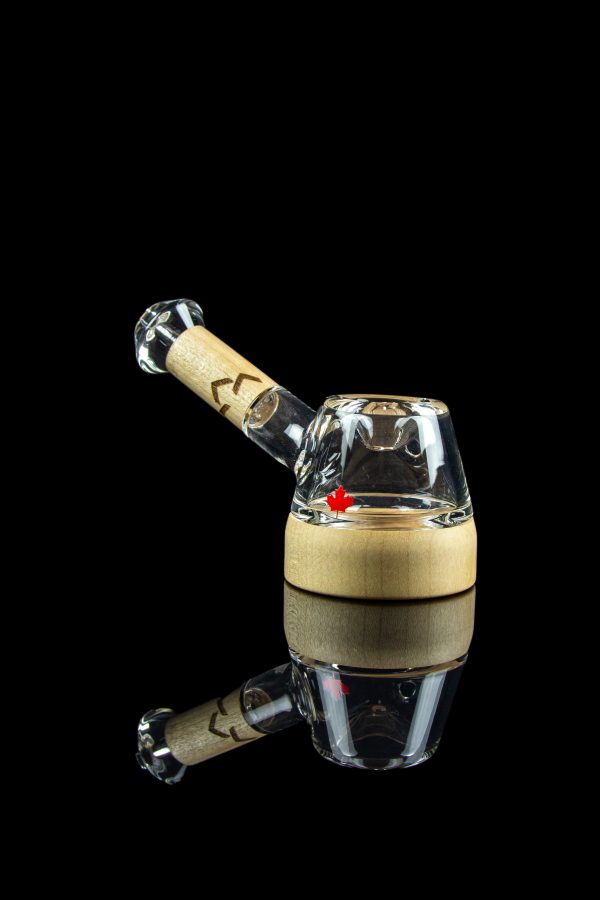 Glass cannabis oil rig with a wooden base and clear glass mouthpiece, reflected on a black surface.