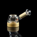 Glass cannabis water pipe with a wooden accent and reflective surface.