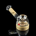 Glass bubbler with a maple leaf design, reflecting on a black surface.