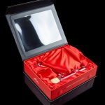 Luxurious red gift box with a clear window displaying cannabis accessories.