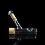 Clear glass water pipe with a maple leaf logo, reflecting on a black surface.