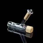 Clear glass water pipe with a textured gold mouthpiece, reflecting on a glossy black surface.