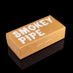 Cardboard box for “Smokey Pipe” titanium pipe, reflecting on a glossy black surface.