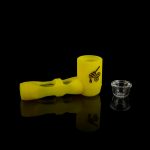 Yellow glass pipe and small cannabis concentrate container on a reflective black surface.