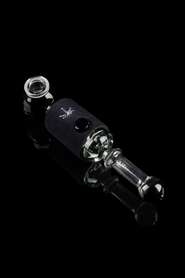 Black glass cannabis oil rig with a leaf design, isolated on a black background.