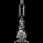 Clear glass water pipe (rig) with intricate bubbler design, isolated on black.