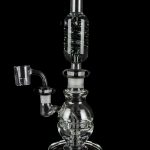 Clear glass dab rig with intricate bubbler design and quartz nail, isolated on black.