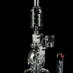Clear glass water pipe (rig) with a quartz banger, displayed on a reflective surface.