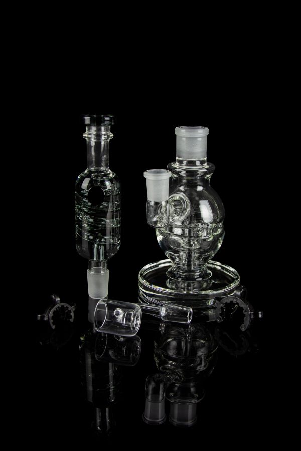 Clear glass dab rigs and accessories displayed on a reflective black surface.