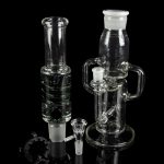 Clear glass bongs and smoking accessories displayed on a black reflective surface.