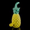 Yellow glass pineapple water pipe with green accents, reflecting on a black surface.