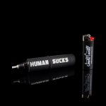 Black cannabis pipe and accessories with bold white and red text reading "HUMAN SUCKS" and a lighter beside it, against a black background.