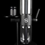 Black glass cannabis rig with a cylindrical percolator chamber and a branded emblem.
