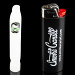 White glass pipe with a cartoon face design next to a black lighter branded with “Smoke Cartel” and website address.