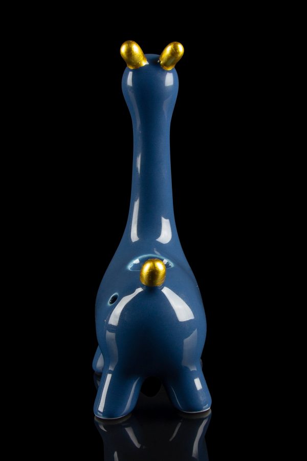Blue glass water pipe shaped like a giraffe with gold accents, reflecting on a black surface.