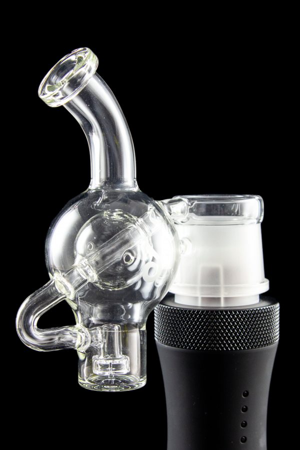 Clear glass water pipe (rig) with a skull-shaped bubbler attached to a black electronic heating device, isolated on a black background.