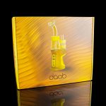 Gold packaging for a Daab cannabis concentrate vaporizer, reflected on a glossy surface.