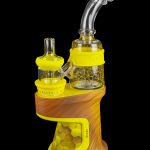 Electric dab rig with a glass bubbler, featuring a woodgrain base and yellow accents.