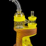 A portable cannabis vaporizer (enail) with a glass water pipe attachment, featuring a wooden base and yellow accents.