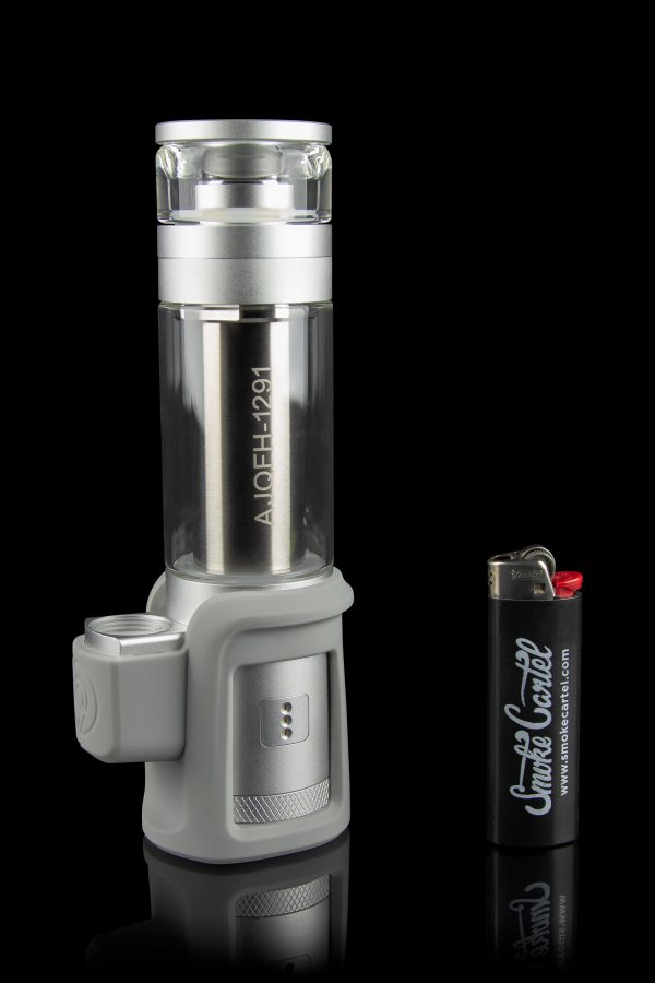 A silver and black electronic dab rig with a glass water pipe attachment, positioned next to a lighter with cannabis-related branding.