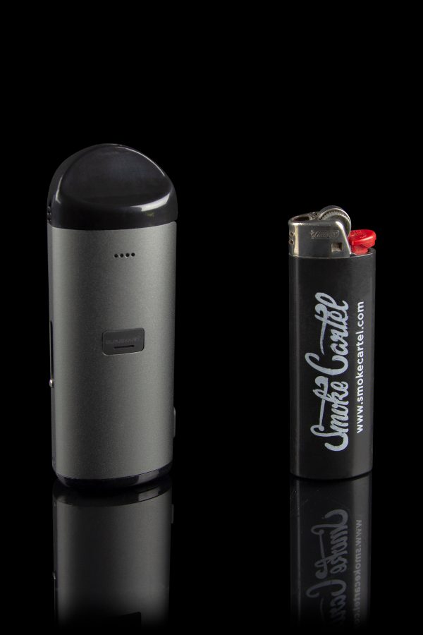 Black cannabis vaporizer pen and lighter with “Smoke Cartel” branding, displayed on a reflective surface.
