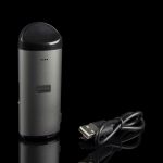 Sleek, metallic cannabis vaporizer pen with a USB charging cable, displayed on a reflective black surface.