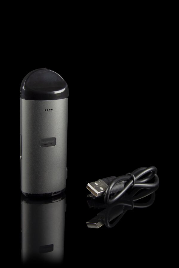 Sleek, metallic cannabis vaporizer pen with a USB charging cable, displayed on a reflective black surface.