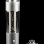 Silver cannabis e-rig with glass bubbler and disassembled magnetic base on a reflective black surface.