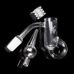 Clear glass dab rig with attachments, including a bowl, carb cap, and nail, against a black background.