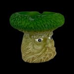 Green glass mushroom ashtray with sculpted facial features.