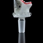A studio shot displays the Empire Glassworks "Jawsome" Bowl Piece, a shark-shaped glass piece reflecting on a dark surface.