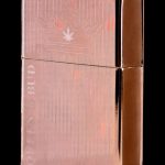 Copper-colored lighter engraved with a cannabis leaf and the text “OTTEN & BUD”.
