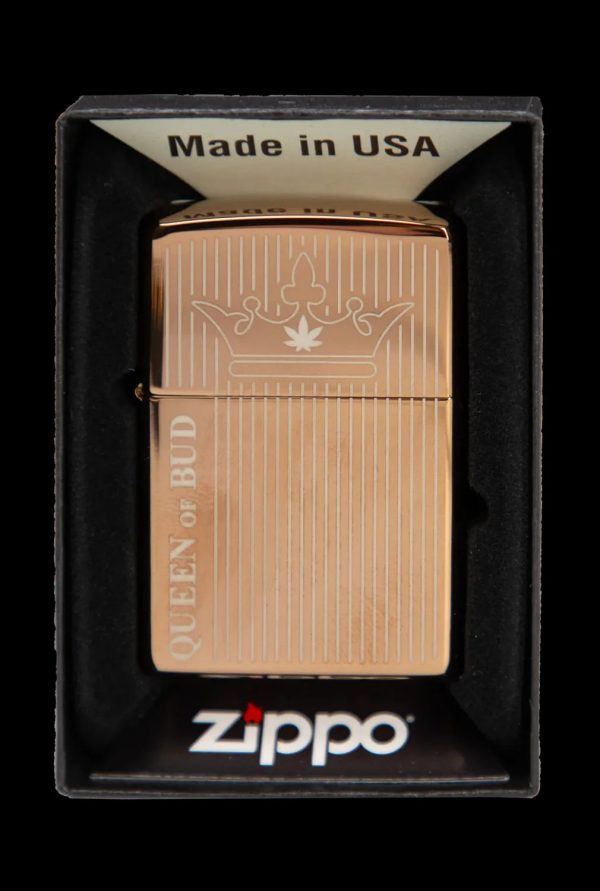 Gold Zippo lighter with a cannabis leaf crown design and "Queen of Bud" text, in its packaging.
