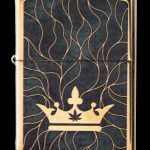 Gold Zippo lighter with a black background featuring a golden crown and cannabis leaf design.