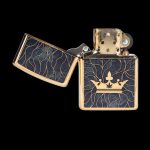 Zippo lighter with a black and gold design featuring a crown and cannabis leaf.