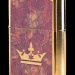 Gold Zippo lighter with a purple and gold swirling pattern and a cannabis leaf-topped crown.
