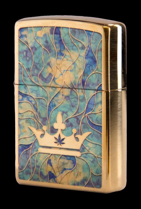 Gold Zippo lighter with a swirling teal and gold pattern and a crown featuring a cannabis leaf.