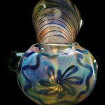 Iridescent glass pipe with floral pattern against a black background.