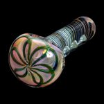 Handblown glass pipe with iridescent swirls and green leaf patterns against a black background.