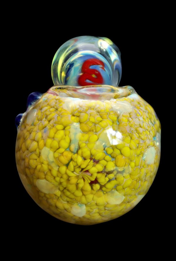 Yellow and red speckled glass cannabis water pipe against a black background.