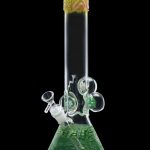 Green glass bong with intricate swirling patterns and bubble percolator, isolated on black.