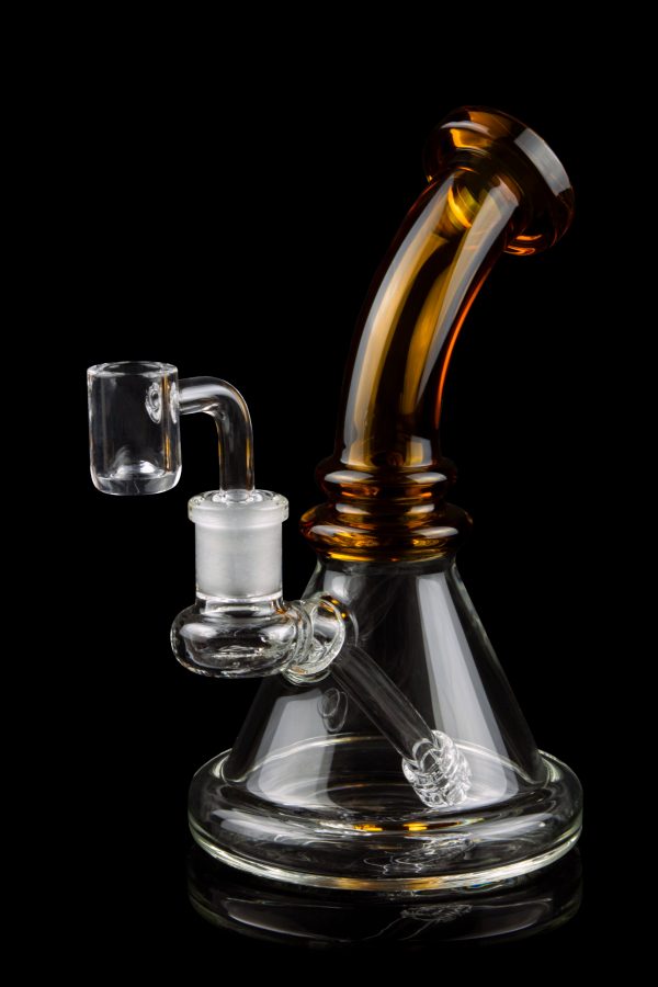 Amber and clear glass dab rig with quartz banger, isolated on a black background.