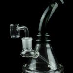 Glass dab rig with quartz banger, isolated on a black background.