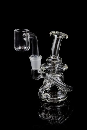 Clear glass dab rig with intricate design and quartz banger.