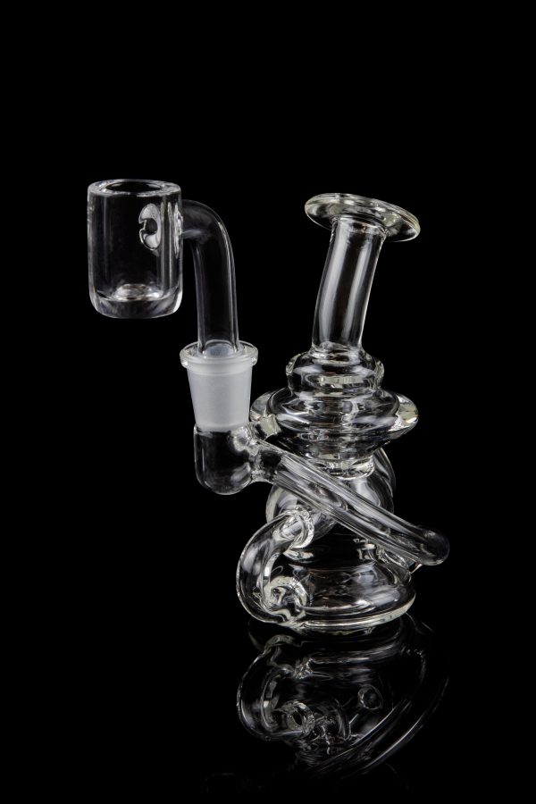 Clear glass dab rig with intricate design and quartz banger.