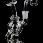 Clear glass dab rig with quartz banger, isolated on black.