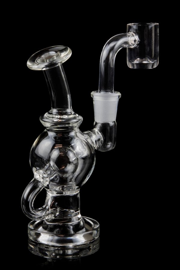 Clear glass dab rig with quartz banger, isolated on black.