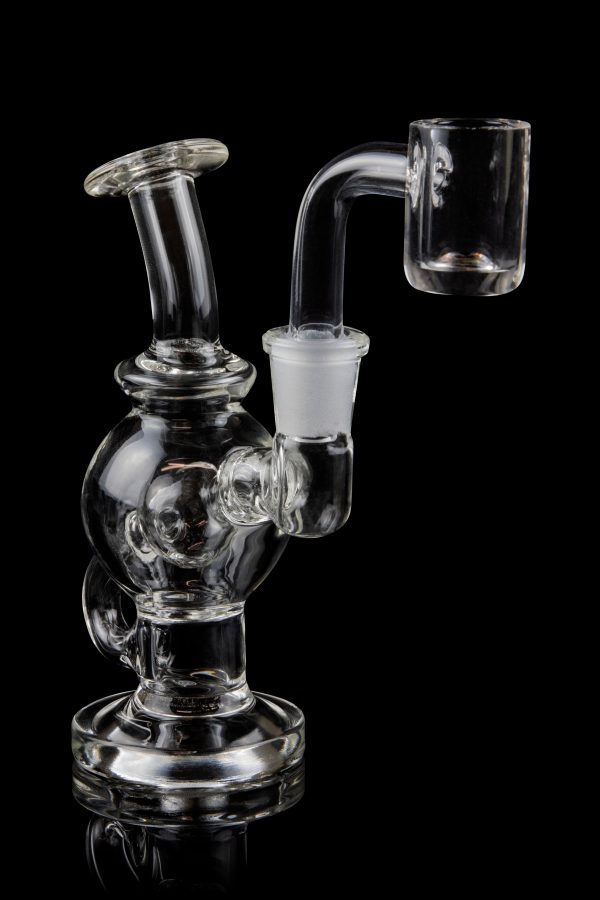 Clear glass dab rig with a quartz banger, isolated on a black background.